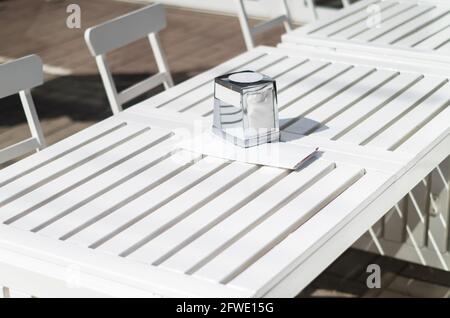 Selective focus. White wooden tabletop against the backdrop of the kitchen counter (room) with inverted glass goblets and party glasses. Stock Photo