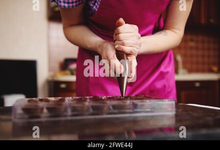 chocolatier pouring caramel filling into chocolate mold preparing handmade  candy Stock Photo - Alamy