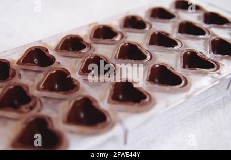 Empty handmade chocolate molds for filling and making candies at home on a white surface. Manufacturing handmade chocolates at home . Concept of World Stock Photo