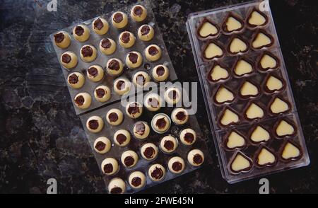 Closeup of squeezing filling of salted caramel cream from confectionery bag  into candy molds for preparing handmade chocolate pralines Stock Photo -  Alamy