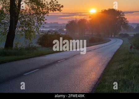 Asphalt road running through the countryside at sunrise Stock Photo