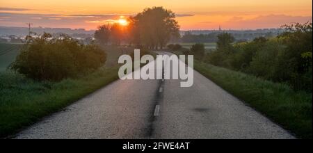 Asphalt road running through the countryside at sunrise Stock Photo