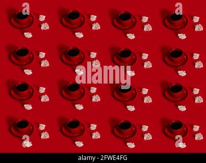 Pattern of ceramic coffee cup with coffee in a red saucer, next to a crumpled paper wrapper from a chocolate praline,isolated on red background with s Stock Photo