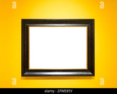 wide black wooden picture frame with cutout canvas on horizontal yellow wall Stock Photo