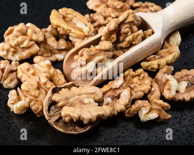 wooden scoop in heap of peeled walnuts on black plate closeup Stock Photo