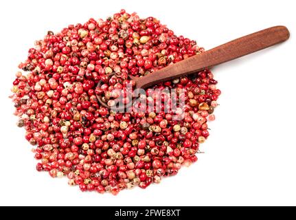wood spoon on pile of pink peppercorns (Baie rose) on white background Stock Photo