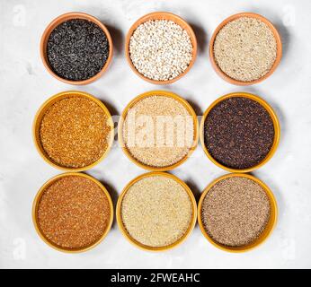 top view of various bird seeds in round ceramic bowls on gray concrete board Stock Photo