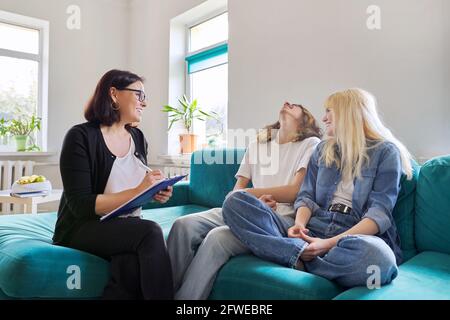 Professional female social worker, teacher, counselor, psychologist talking with teenagers Stock Photo