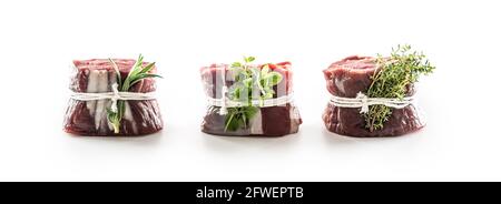 Three raw steams wrapped by a twine with fresh rosemary, thyme and oregano on an isolated white background. Stock Photo