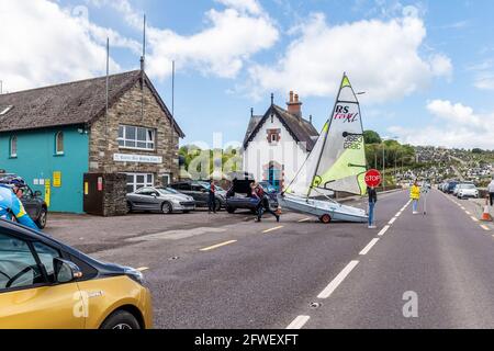 Bantry, West Cork, Ireland. 22nd May, 2021. The sun shone on Bantry this morning with many locals and visitors taking full advantage of the good weather. Bantry Bay Sailing Club's Saturday morning sailing session attracted many sailors. Club members cross the road with their dinghies heading for the clubhouse. Credit: AG News/Alamy Live News Stock Photo