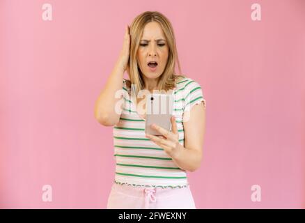 young pretty woman shouting aggressively, looking angry, frustrated, outraged or annoyed, screaming holding a smart telephone Stock Photo