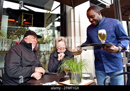 Essen, Germany. 22nd May, 2021. Nelson Müller (r), star chef, serves the regulars, the Kron family, in the outdoor area of his restaurant Müllers. After 7 months of Corona forced break, the outdoor gastronomy in Essen is open again for the Whitsun weekend. Since the weather is bad, not all restaurants have opened their outdoor areas. Credit: Caroline Seidel/dpa/Alamy Live News Stock Photo