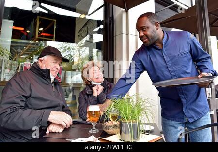 Essen, Germany. 22nd May, 2021. Nelson Müller (r), star chef, serves the regulars, the Kron family, in the outdoor area of his restaurant Müllers. After 7 months of Corona forced break, the outdoor gastronomy in Essen is open again for the Whitsun weekend. Since the weather is bad, not all restaurants have opened their outdoor areas. Credit: Caroline Seidel/dpa/Alamy Live News Stock Photo