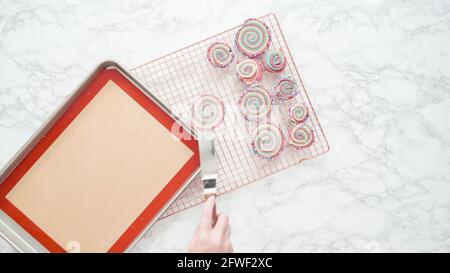 Step by step. Flat lay. Cooling freshly baked bake red, white, and blue pinwheel sugar cookies on a cooling rack. Stock Photo