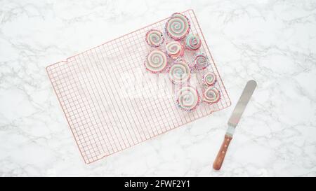 Step by step. Flat lay. Cooling freshly baked bake red, white, and blue pinwheel sugar cookies on a cooling rack. Stock Photo