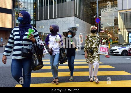 Kuala Lumpur, Malaysia. 22nd May, 2021. People wearing face masks walk across a street in Kuala Lumpur, Malaysia, May 22, 2021. Malaysia announced further tightening restrictions on Saturday under its nationwide movement control order (MCO) as the country's accumulative COVID-19 cases topped 500,000. Credit: Chong Voon Chung/Xinhua/Alamy Live News Stock Photo