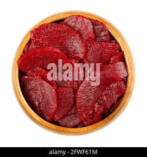 Sliced pickled beetroot slices, in a wooden bowl. Cooked, cut and preserved deep red beets, used as salad or added to a meal. Close-up, from above. Stock Photo
