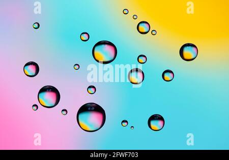 Beautiful coloured diffraction effects from water droplets on glass against a multicoloured background Stock Photo