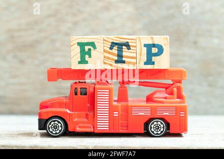 Fire ladder truck hold letter block in word FTP (Abbreviation of File Transfer Protocol) on wood background Stock Photo