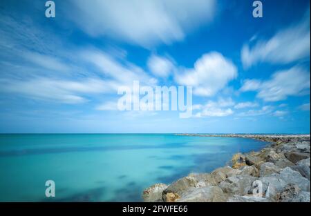 Blue sky with moving white clouds over the blue green colored Gulf of Mexico at the Jetty In Venice Florida USA Stock Photo