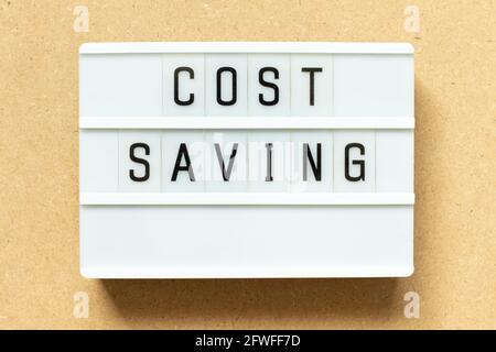 Lightbox with word cost saving on wood background Stock Photo