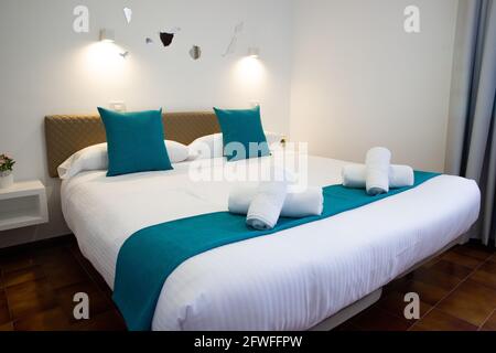 Double bed with the folded towels on top, inside a bedroom. Stock Photo