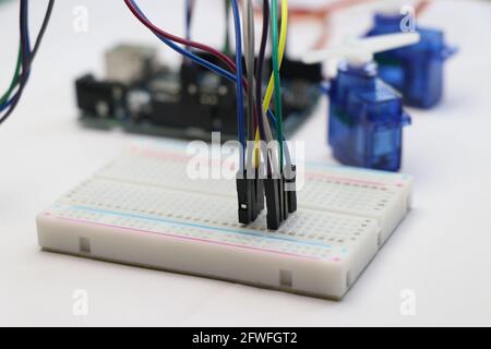 Breadboard with jumper wires connected along with arduino uno and micro servo on background. Arduino project concept Stock Photo