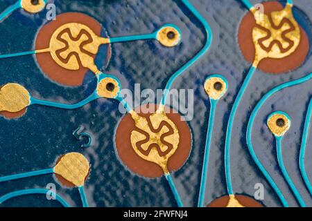 Abstract macro-photo of key contact pads, traces & through-holes on blue printed circuit board (pcb) from old credit card size Canon calculator. Stock Photo