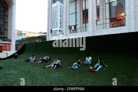 22nd May, 2021. New York City, USA.  People enjoying the14,000 square foot synthetic grass carpet set up in the Josie Robertson Plaza in New York City's Lincoln Center.  The lawn, designed by renowned set designer Mimi Lien, is constructed of recyclable, biobased SYNLawn, which will be used for Lincoln Center performances through its 'Restart Stages' program, designed to re-stimulate connection to the arts as the city emerges from the pandemic. Credit: Adam Stoltman/Alamy Live News Stock Photo