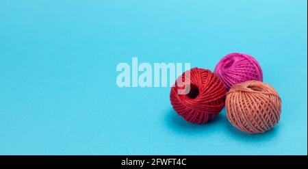 colorful wool balls, red, brown, and fuchsia with light blue background, panorama Stock Photo