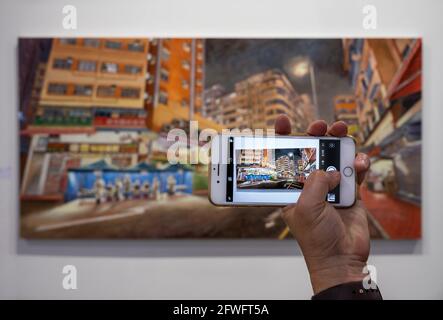 Hong Kong, China. 21st May, 2021. A visitor takes a photo with a smartphone of a painting depicting a scene of Covid-19 testing facility, during the Art Basel Hong Kong at the convention and exhibition centre, the exhibition is open to the public from May 21st to May 23rd. Credit: SOPA Images Limited/Alamy Live News Stock Photo