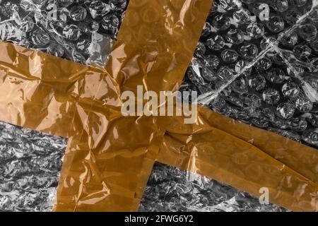 Brown wrinkled adhesive tape on black gray bubble wrap. Sellotape. Abstract background Stock Photo