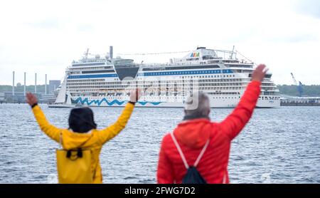 Kiel, Germany. 22nd May, 2021. The Aida cruise ship 'AIDAsol' leaves the harbor as people wave on the shore. The crisis-ridden cruise industry starts the season after several months of corona break in Germany. (to dpa 'Aida opens cruise season from Kiel with Baltic Sea tour') Credit: Daniel Bockwoldt/dpa/Alamy Live News Stock Photo