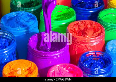 Use a spoon to scoop the purple paint in the glass bucket. colorful of ink background. Stock Photo