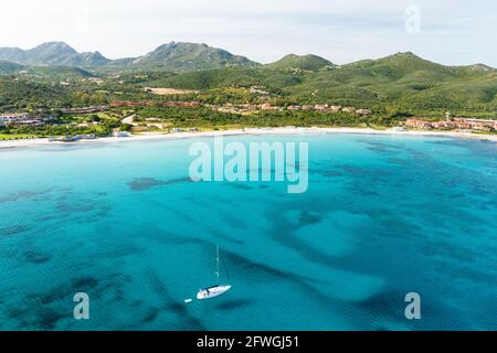 View from above, stunning aerial view of a sailboat sailing on a turquoise and transparent water. Porto Rotondo, Costa Smeralda, Sardinia, Italy. Stock Photo