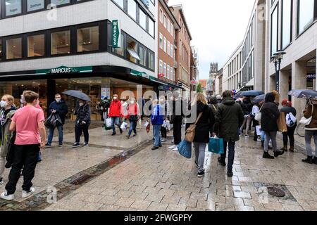 Münster, NRW, Germany. 22nd May, 2021. Crowds gather in the historic city centre of Münster, despite heavy rain, as it becomes the first city in North Rhine-Westphalia to be allowed to open up indoor drinking and dining (with negative test or vaccination), and shopping without a test or appointment (but numbers are restricted). Münster currently has one of the lowest covid incidence rates in NRW at 17/100k and has become a 'model region' to trial slow re-opening of hospitality venues. Credit: Imageplotter/Alamy Live News Stock Photo