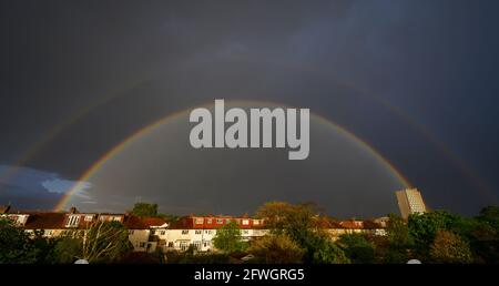 Wimbledon, London, UK. 22 May 2021. Heavy evening downpour ends with a bright double rainbow over houses in suburban London. Credit: Malcolm Park/Alamy Live News.