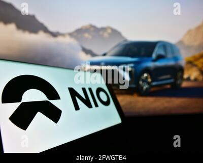 Cellphone with business logo of Chinese electric car manufacturer NIO Inc. on screen in front of website. Focus on center-left of phone display. Stock Photo