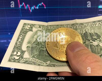 Bitcoin coin on paper bill two Dollars. Selective focus. The electronic schedule of bitcoin, volume trades Stock Photo
