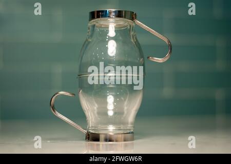 Various glassware - including espresso glasses, cake tray, and pitchers in front of a modern interior tile. Stock Photo