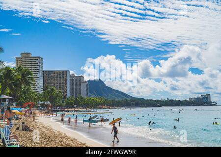Oahu, Hawaii November 15 2019: People enjoying the warm waters off Waikiki beach with Diamond Head in background surfing, sunbathing and relaxing. Stock Photo