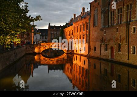 Nocturne canal view of Gothic style buildings and the ancient Blinde Ezelstraat stone bridge in the historic center of Bruges, West Flanders Belgium. Stock Photo