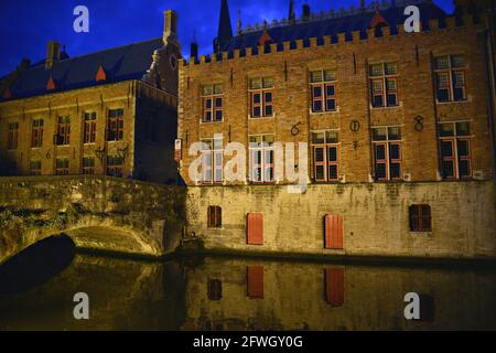 Nocturne canal view of the Gothic style Burg and the ancient Blinde Ezelstraat stone bridge in the historic center of Bruges, West Flanders Belgium. Stock Photo