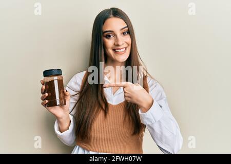 Beautiful brunette young woman holding soluble coffee smiling happy pointing with hand and finger Stock Photo