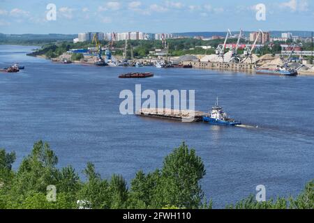 A barge carries cargo on the river. Transportation of wood by river transport. Stock Photo