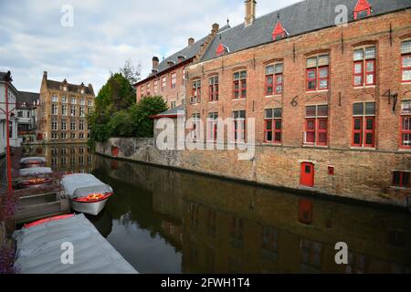 Canal view of the ancient Blinde Ezelstraat with the Gothic style buildings and the traditional river boats in the historic center of Bruges Belgium. Stock Photo