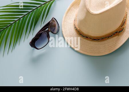 Holiday season, Panama hat, ladies sunglasses, large green leaf of a tropical tree. gently blue background, space for an inscription, summer travel co Stock Photo