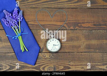 Fathers Day gift. Blue tie, flowers and vintage pocket watch on wooden background Stock Photo