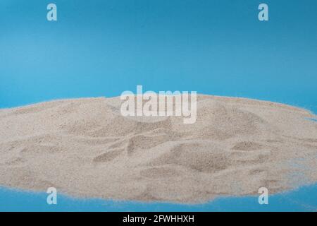 Beach sand pile isolated on blue background. Vacation theme. Stock Photo