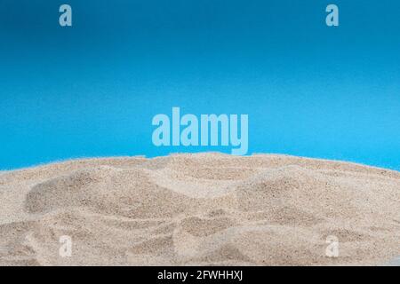 Beach sand pile isolated on blue background. Vacation theme. Stock Photo